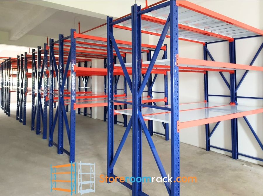Rows of warehouse racking with blue uprights and orange beams running down a warehouse aisle